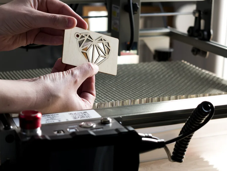 Close-up of laser cutting process on a wooden heart design